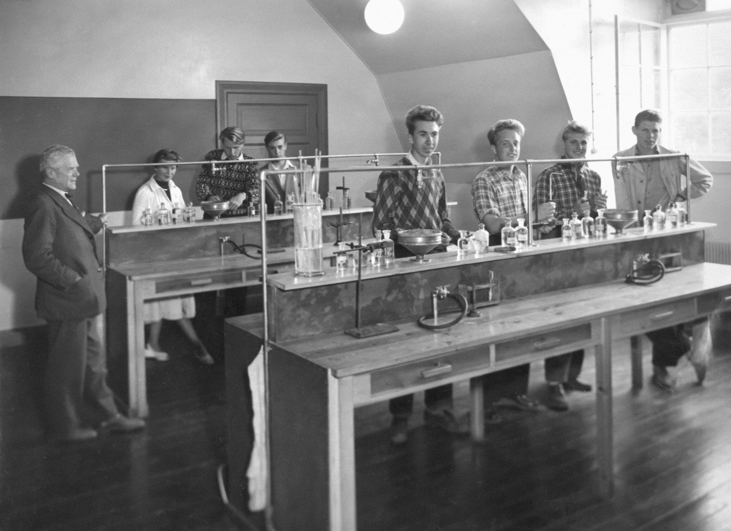 Un istruttore osserva studenti che lavorano con attrezzature chimiche in un laboratorio.