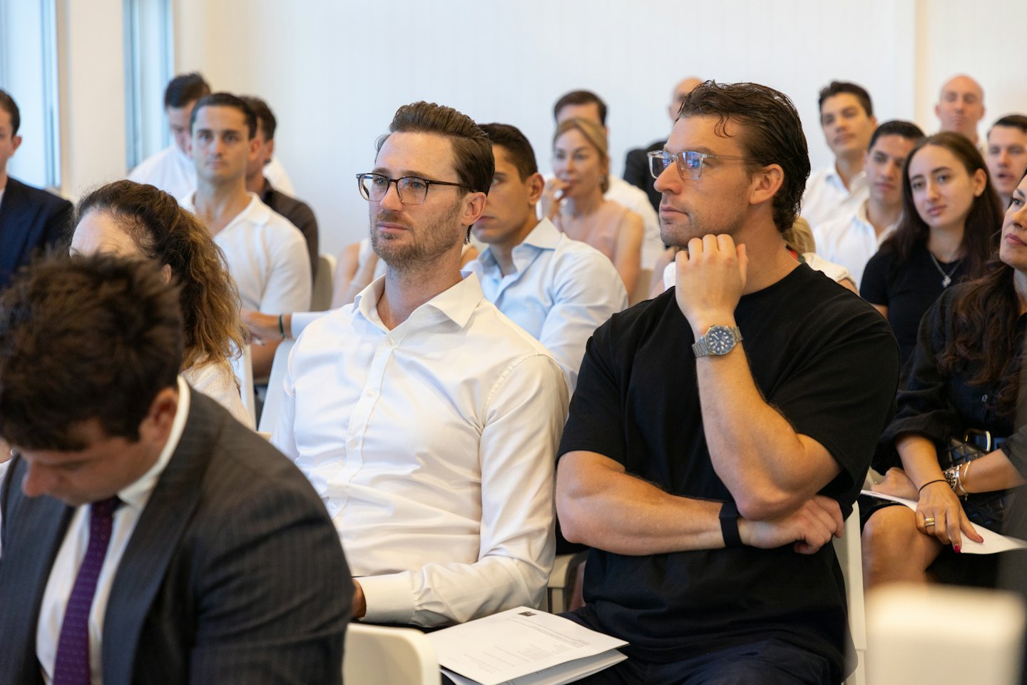 Professionisti diversi ascoltano a un evento aziendale moderno.