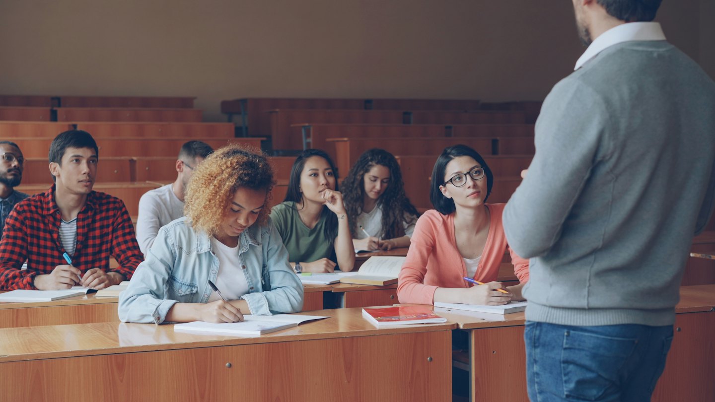 Studenti universitari attenti durante una lezione in un'aula magna.
